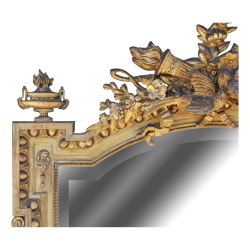 Miroir Louis XVI en bois doré orné de de guirlandes de fleurs.
