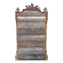 Miroir Louis XVI en bois doré orné de de guirlandes de fleurs.