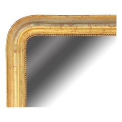 Miroir en bois doré orné d une frise de perles.