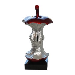 Trognon de pomme rouge et argenté sur socle noir.