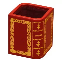 个红色皮革铅笔罐，带有打开书本的金色装饰。