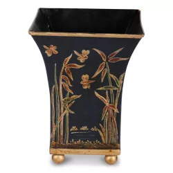 A black and gold metal planter with floral decor