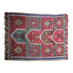Ein „Kelim“-Teppich aus Wolle in den Farben Grün, Rot, Blau, Schwarz und Weiß.