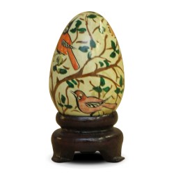 A Russian wooden egg decorated with foliage and birds on a yellow background