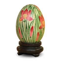 a Russian wooden egg with red flower decoration on a green leaf