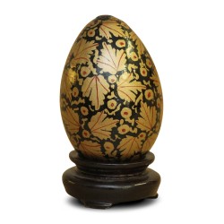 A Russian wooden egg with black and gold floral decoration