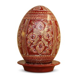 A wooden egg with geometric decoration on a red background