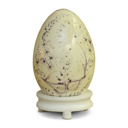 A Russian wooden egg with purple floral decoration on a cream background