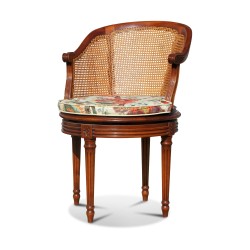 Une assise de bureau tournant Louis XVI en acajou, dossier et assise canné avec coussin